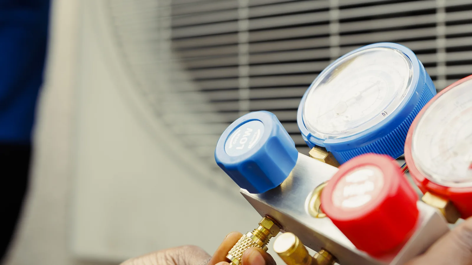 An HVAC technician reading pressure on a set of manifold gauges
