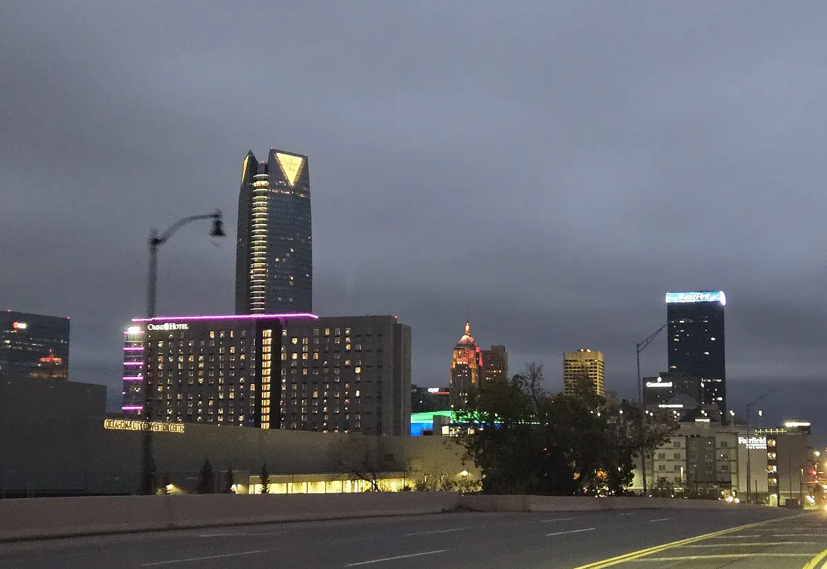 Downtown Oklahoma City at dusk, with lit office towers rising behind the Oklahoma City Convention Center